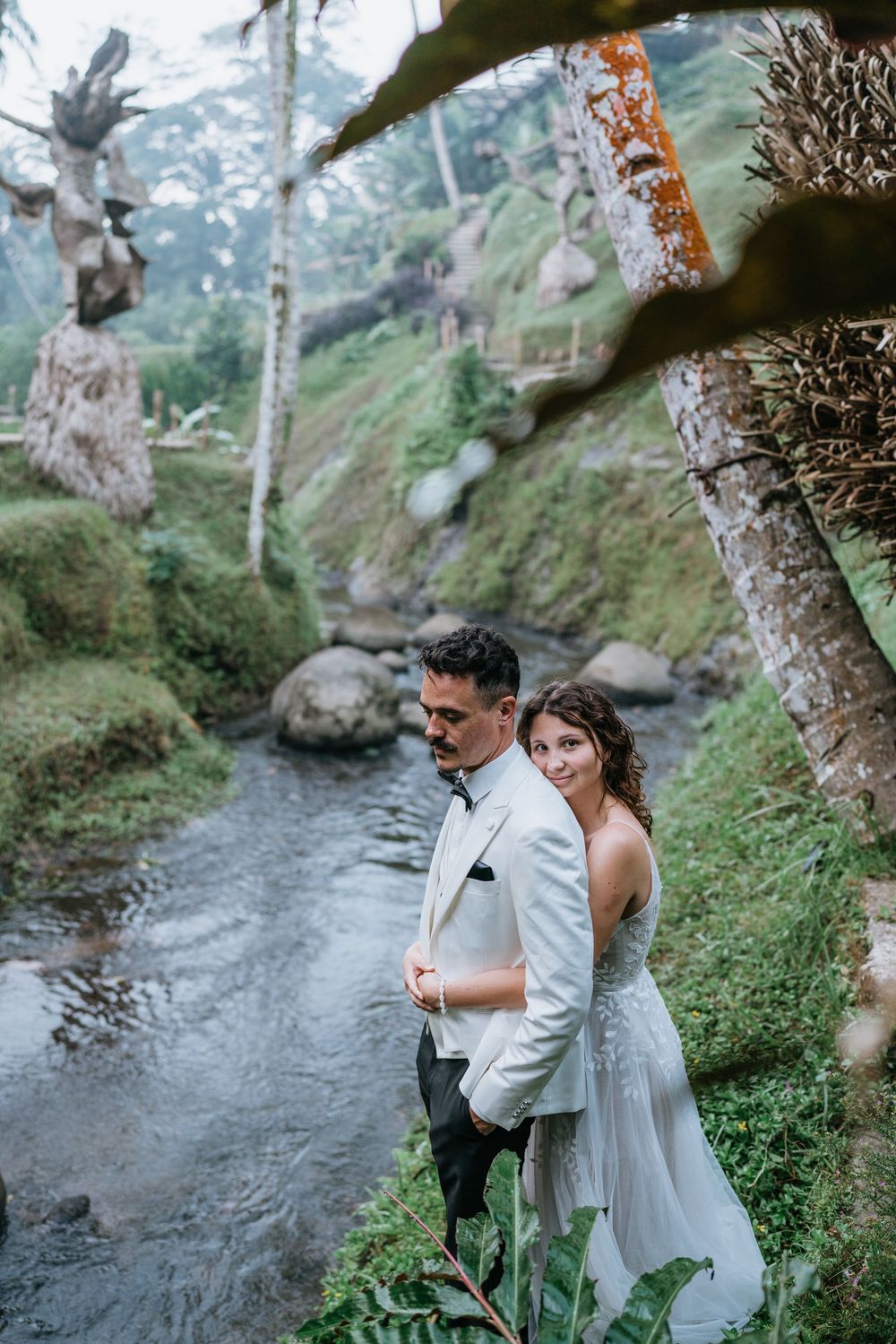 Romantic photoshoot by a flowing stream surrounded by lush tropical foliage.