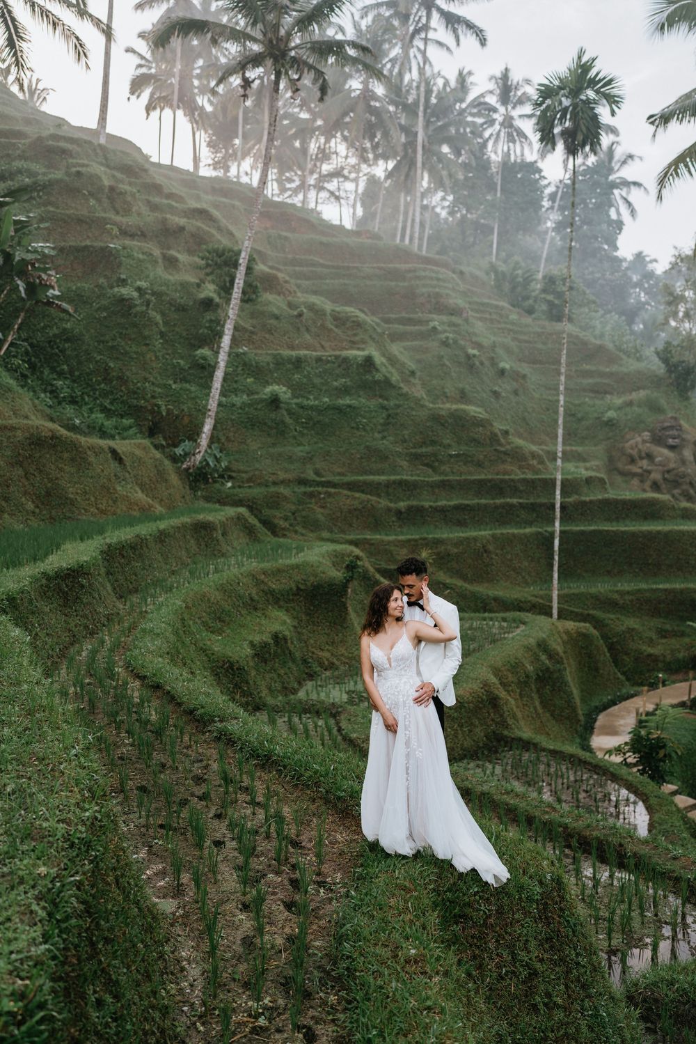 Dreamy wedding photography on terraced rice fields with palm trees in Bali.