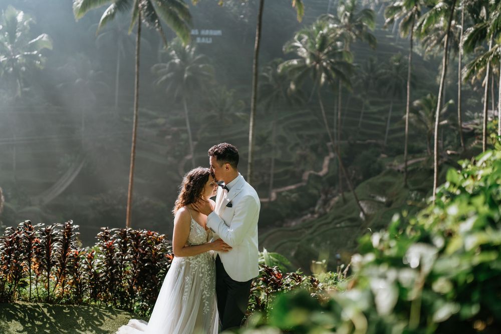 Intimate wedding moment captured against a backdrop of tropical palm trees and natural light.