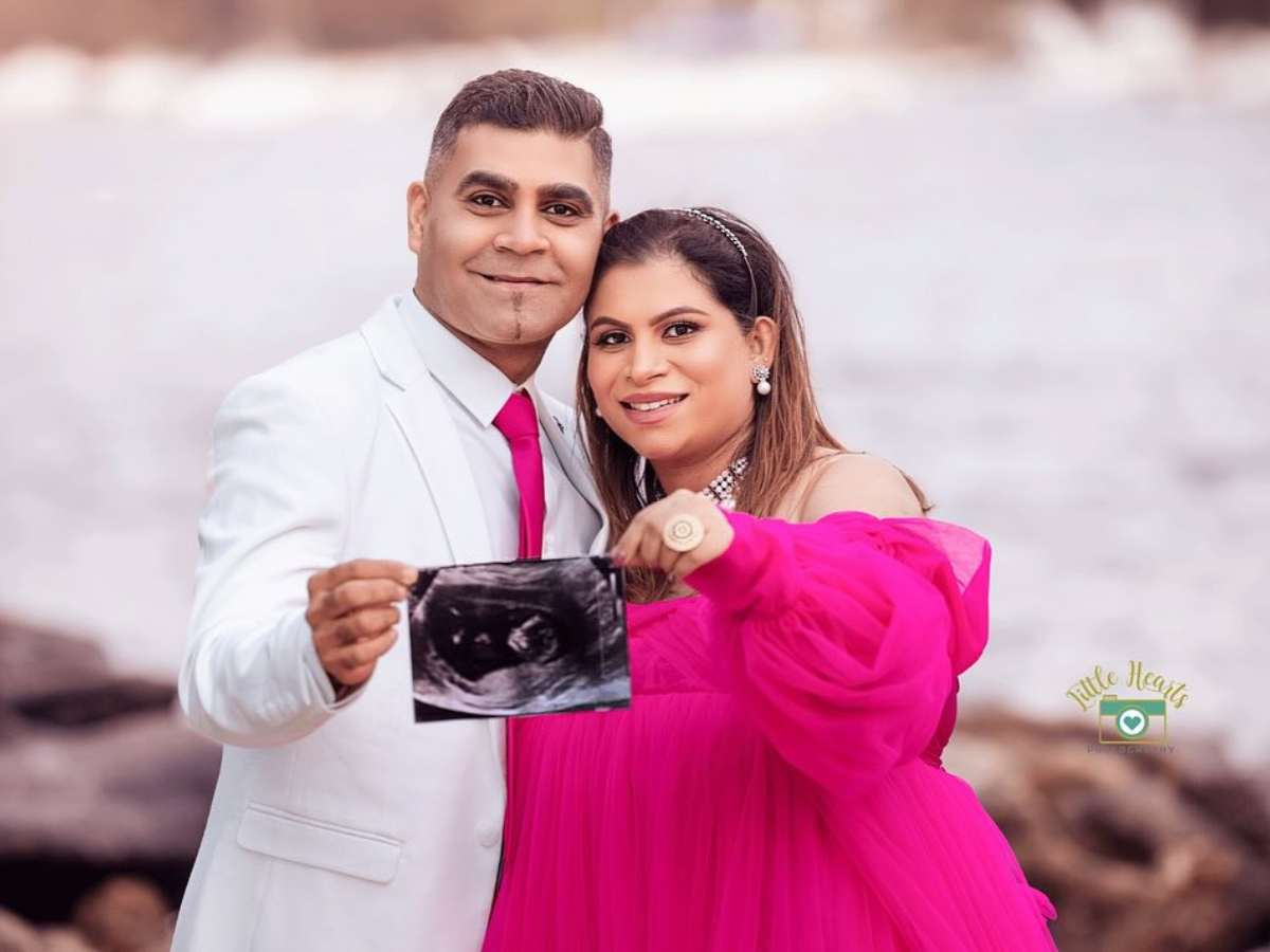 Couple in white and pink attire poses together at a beach for a series of casual engagement photos.