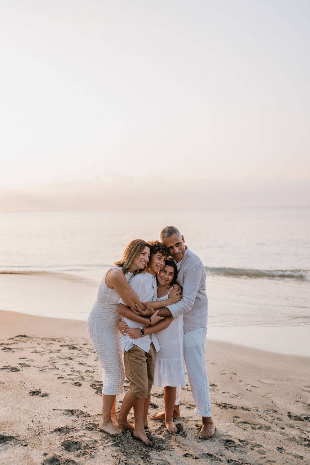 Family sharing intimate moment together on beach during golden hour.