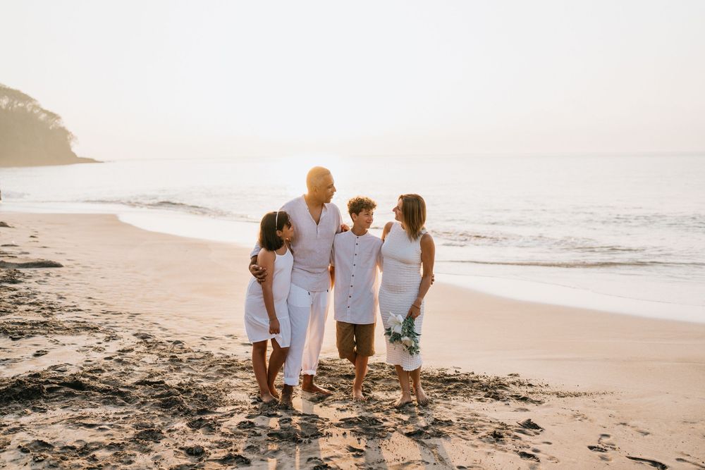 Family walking along shoreline together during sunset at beach.