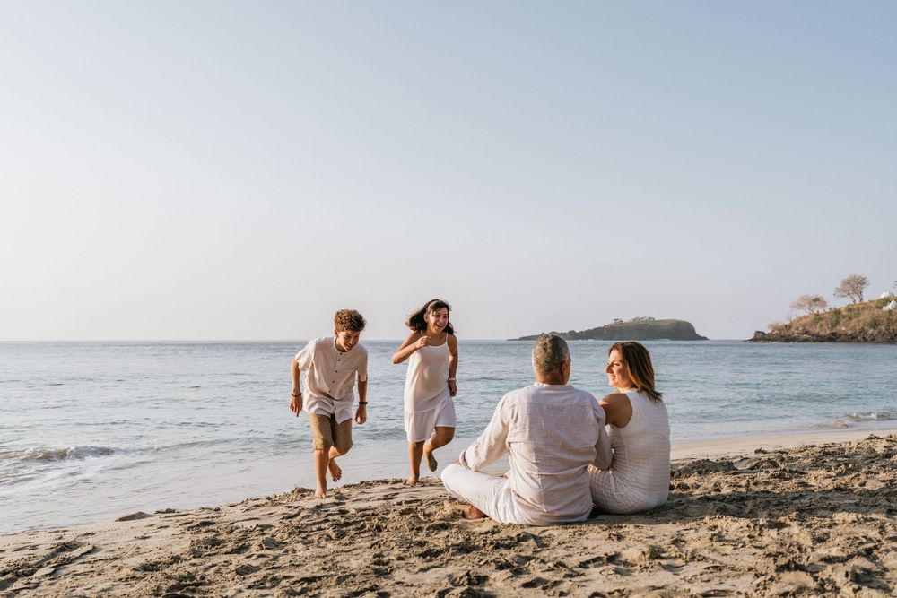 Family members relaxing on sandy beach while enjoying oceanfront views.