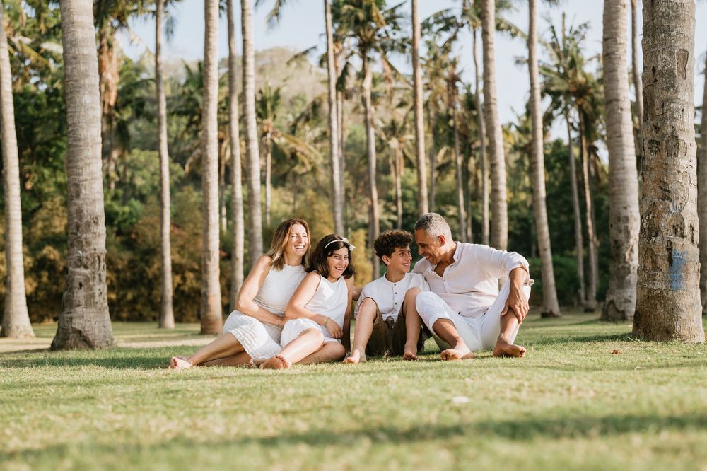 Group lounging on green grass surrounded by towering palm trees in tropical paradise.