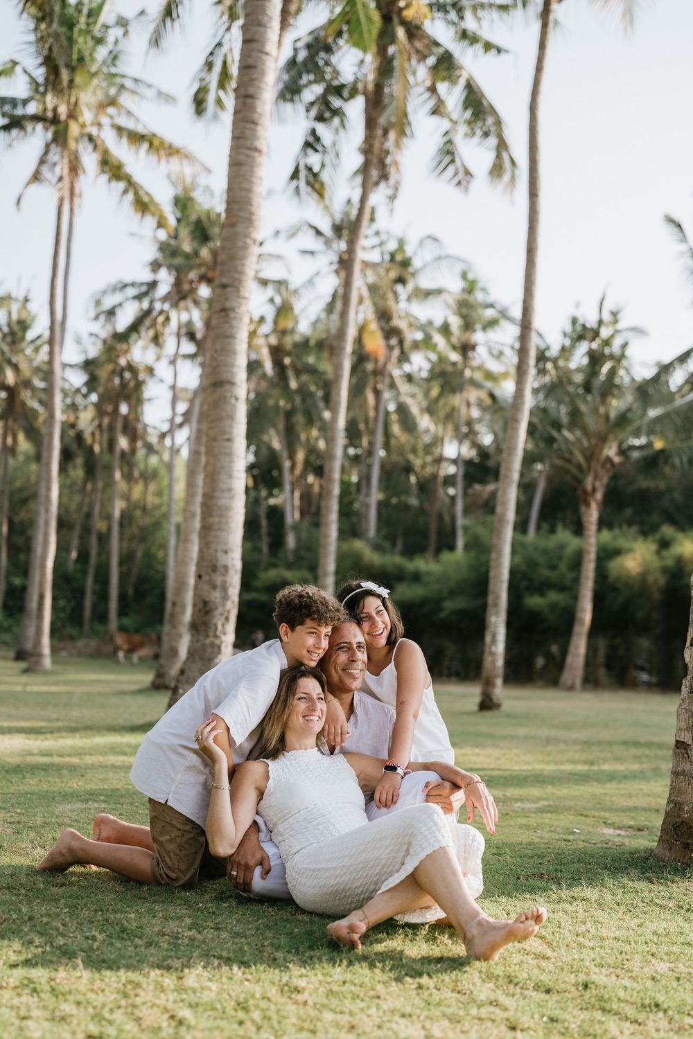 Candid family moment captured while relaxing on grass beneath swaying palm trees.