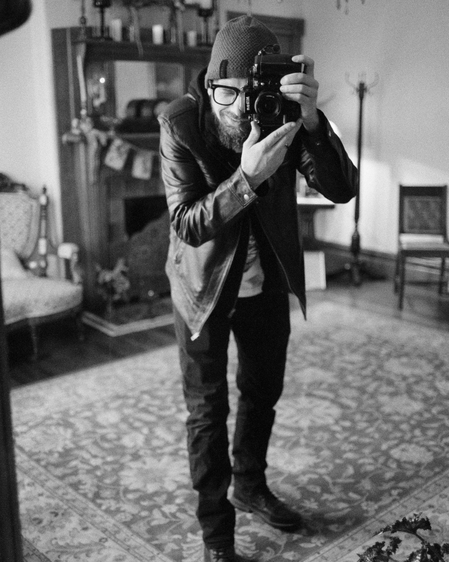 A photographer crouches down while taking a close-up photo on a patterned floor.