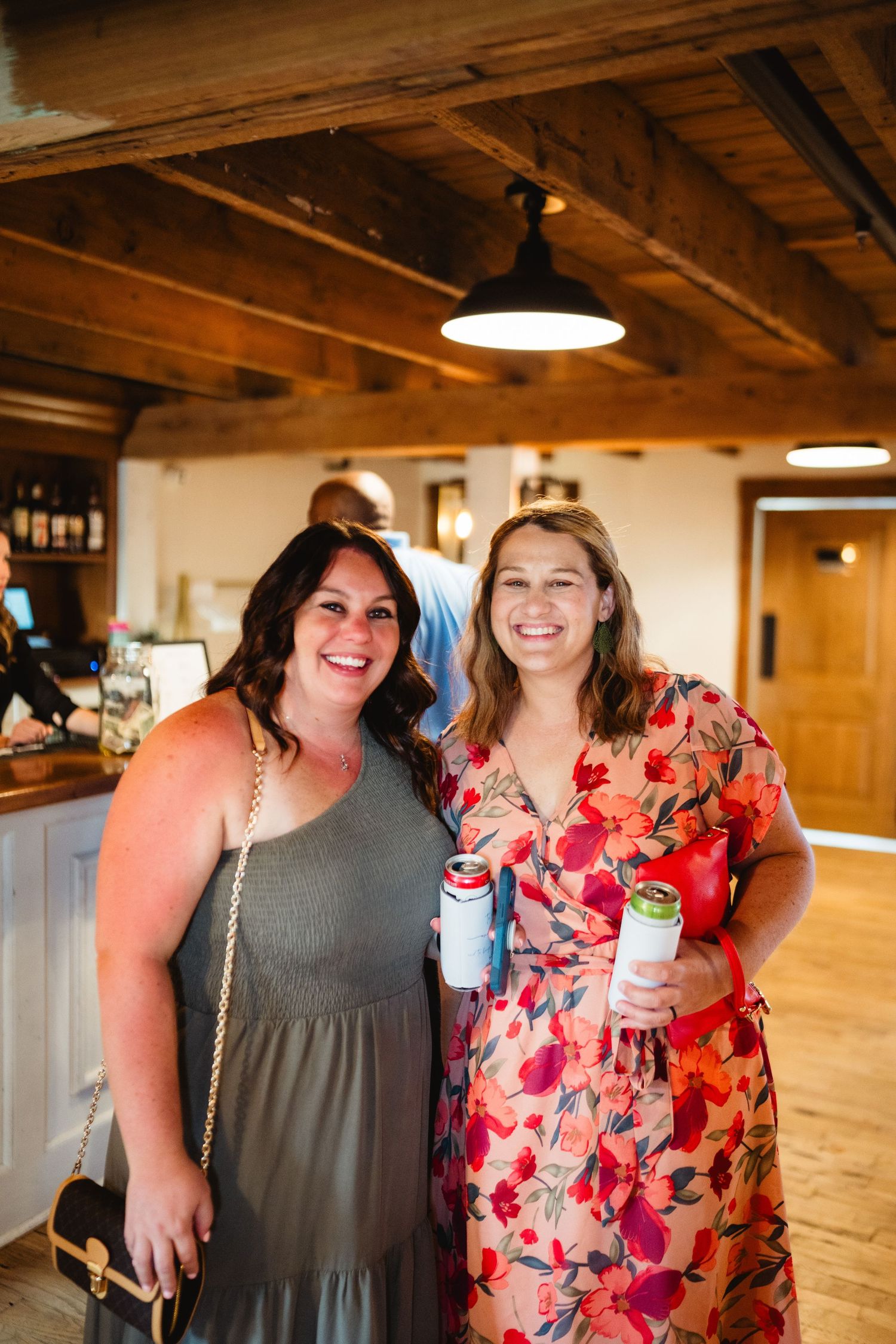 Friends gather and smile together in a rustic indoor venue with wooden beams and warm lighting.