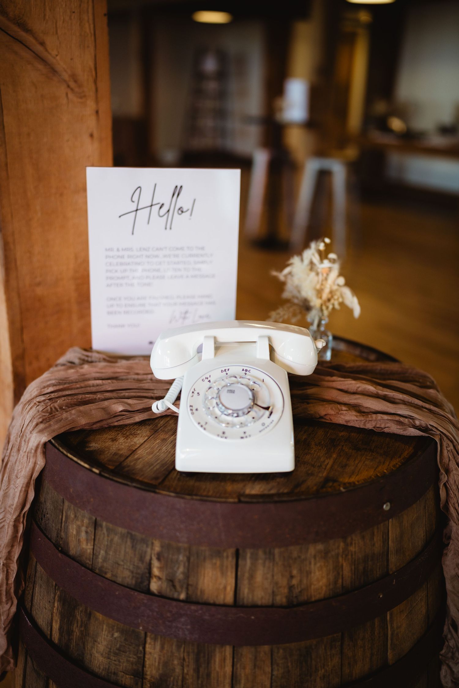 Vintage rotary phone placed on rustic wooden wine barrel displays in sequential arrangement at rustic venue setting.