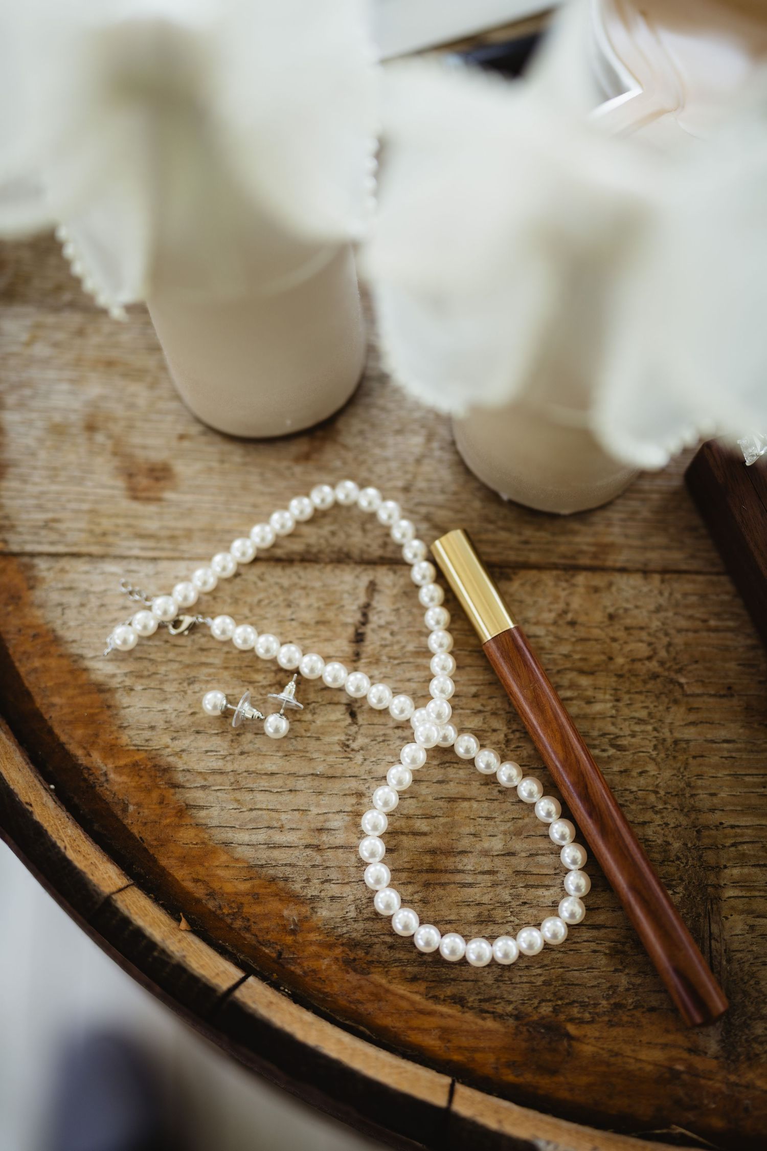 A string of small white pearls arranged in the shape of a heart with a golden chopstick on a rustic wooden surface.