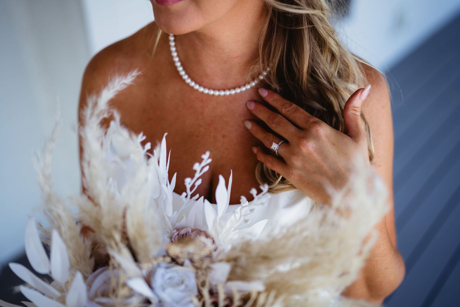 Beautiful shared wedding moment captured with pearls and white feather details in elegant wedding attire.