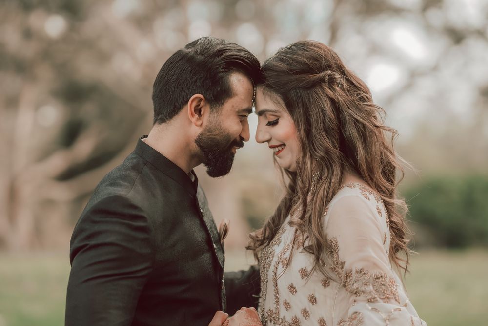 A romantic couple shares an intimate moment outdoors with soft natural lighting and muted earth tones.