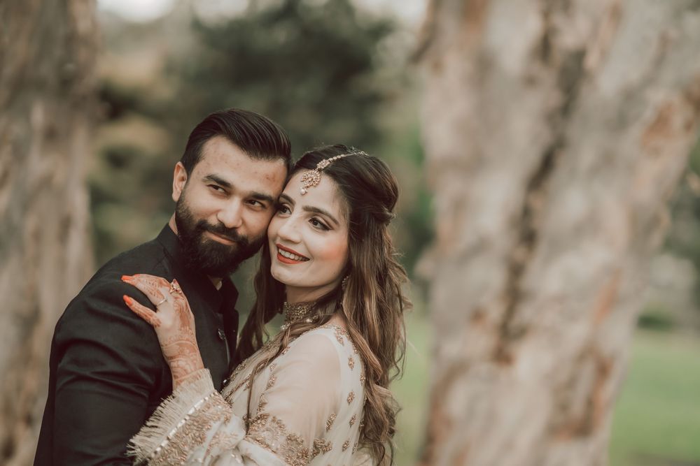 A romantic couple shares tender moments in a rustic outdoor setting with eucalyptus trees in the background.