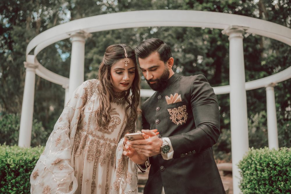 A romantic wedding couple shares an intimate moment together under a white gazebo surrounded by lush greenery.