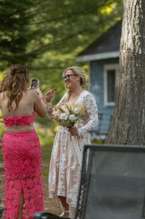 Two attendees in pink and floral dresses enjoying drinks at an outdoor celebration.
