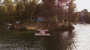Panoramic view of a lake with boats and cottages along the tree-lined shore.