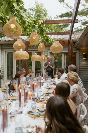 Outdoor dinner party setup with woven pendant lights and elegant table settings.