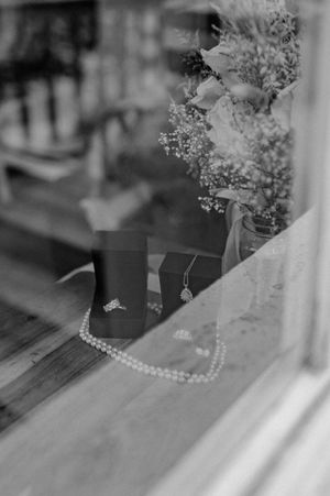 Black and white detail shot of wedding decorations and pearls on a wooden surface.