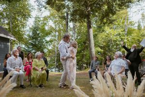 Wedding guests dance and celebrate outdoors in a lush garden setting during a summer celebration.