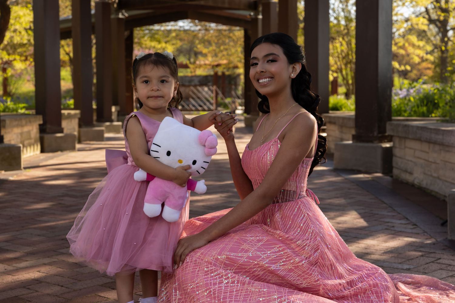Heartfelt portrait of a Sweet 16 girl in a pink gown with her little sister. Emotional family milestones captured by Alex T Photography.