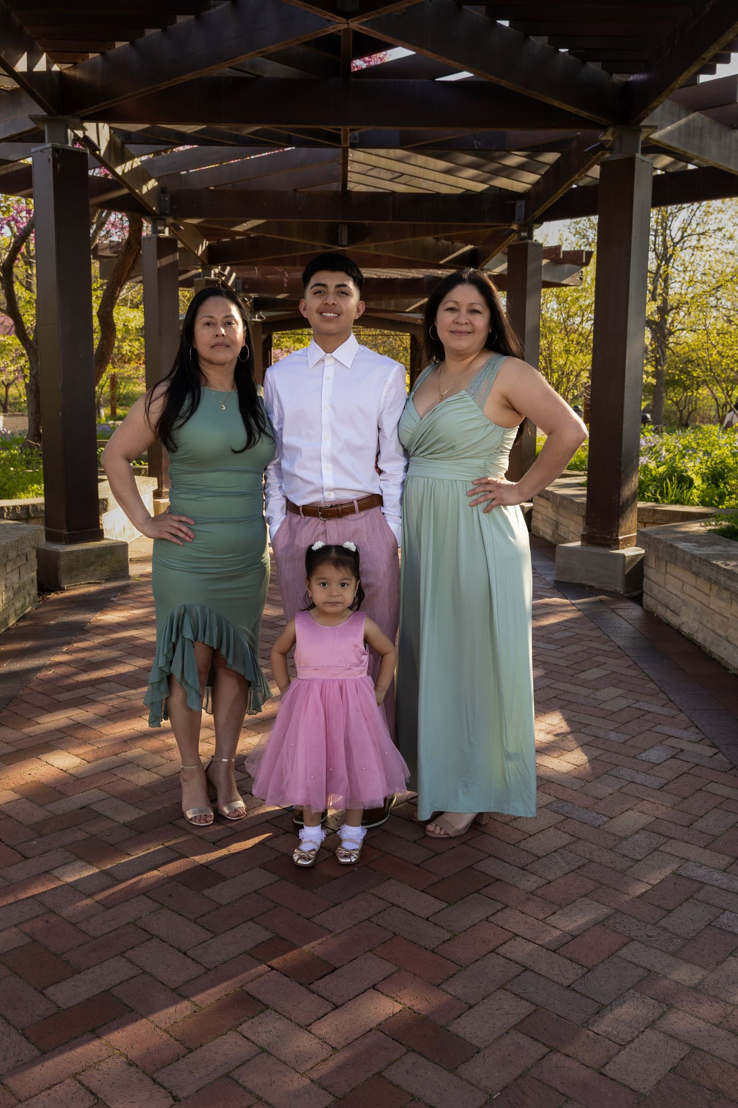 A family of four posing under a wooden garden structure. Professional family portrait session in a Lake County park by Alex T Photography.
