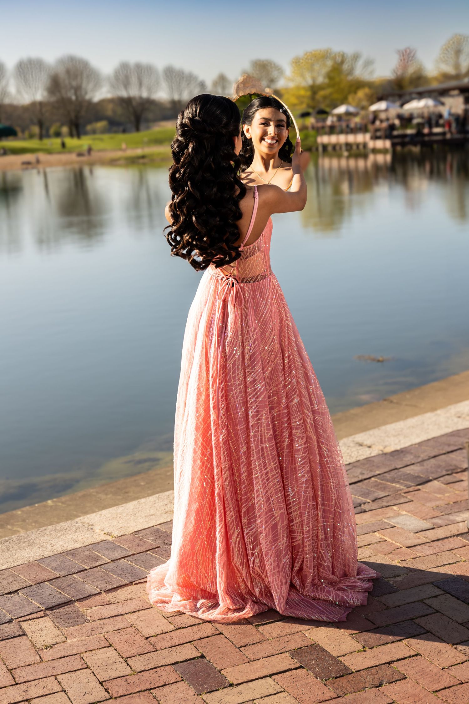 A woman in a pink gown posing by the water at Independence Grove. Elegant sunset lifestyle portraits in Lake County by Alex T Photography.