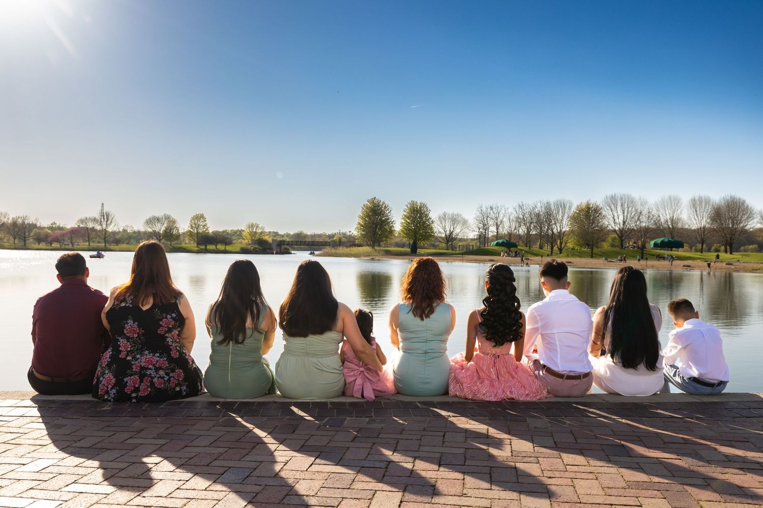 A large family group sitting together on a dock at Independence Grove. Beautiful waterfront family portraits in Libertyville by Alex T.