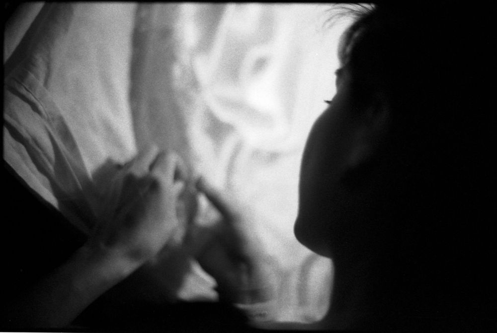 Black and white profile of a woman working with delicate white fabric in soft light.