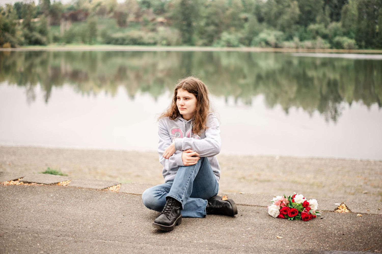 A series of lakeside photos showing someone sitting on the ground with red roses and reflective water in the background.