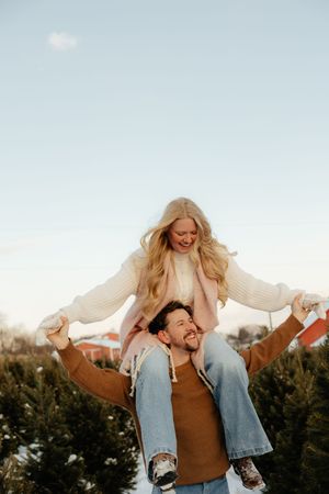 Two people laughing and having fun outdoors during golden hour, with one person being lifted in a playful moment.