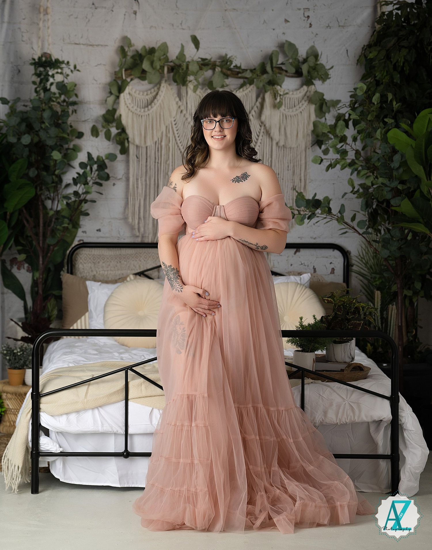 A dreamy boudoir photo session features a romantic peach-colored tulle gown on a vintage iron bed with greenery backdrop.