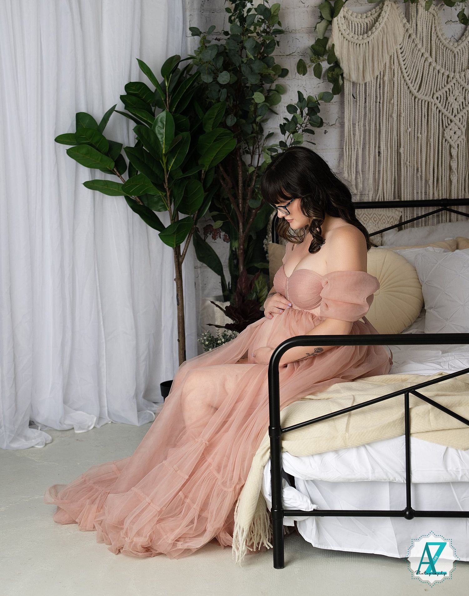 Romantic pink tulle gown showcased in bedroom setting with white bedding and decorative wall hangings.