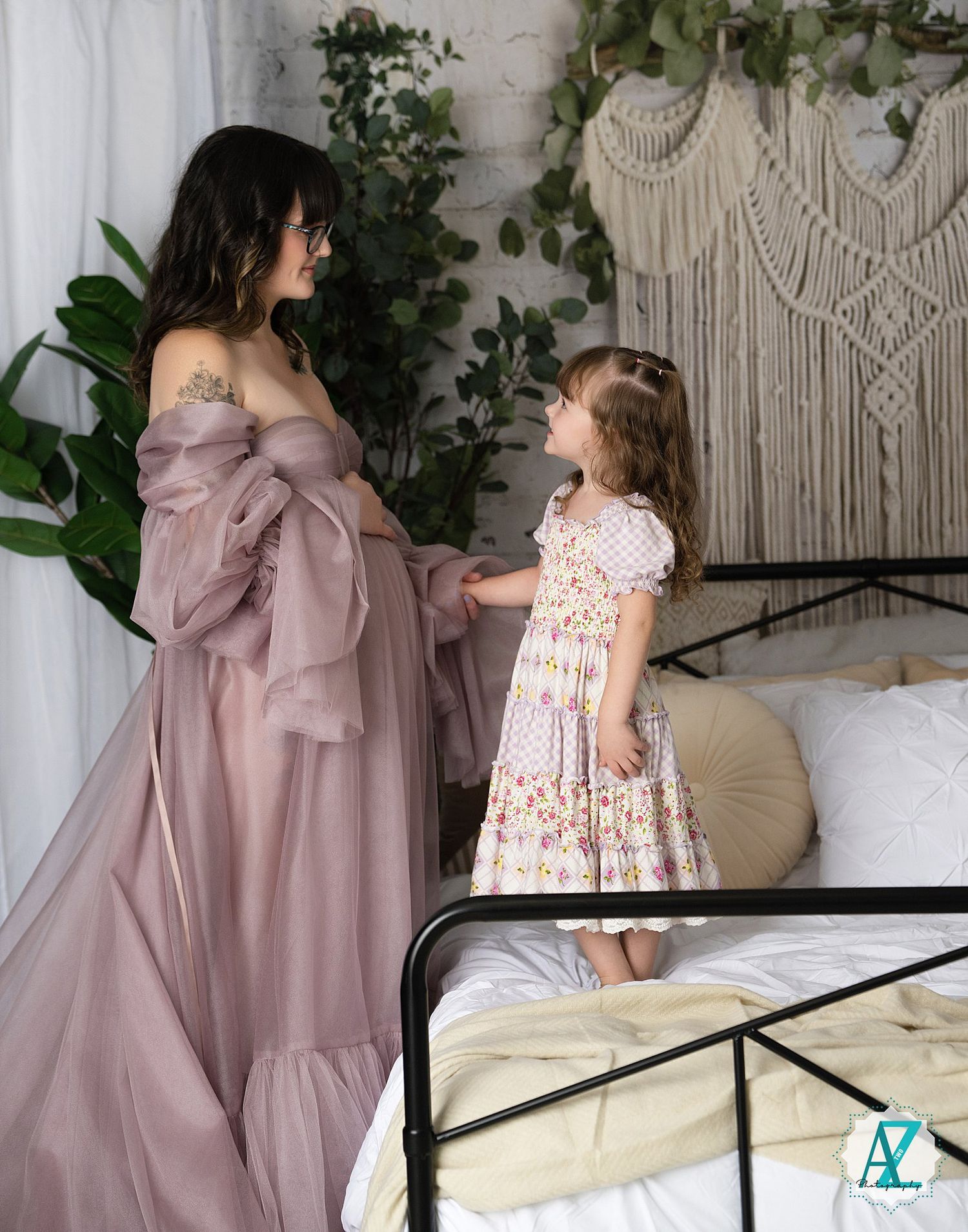 Elegant mauve and floral dresses displayed in bedroom setting with macrame wall decor and greenery accents.