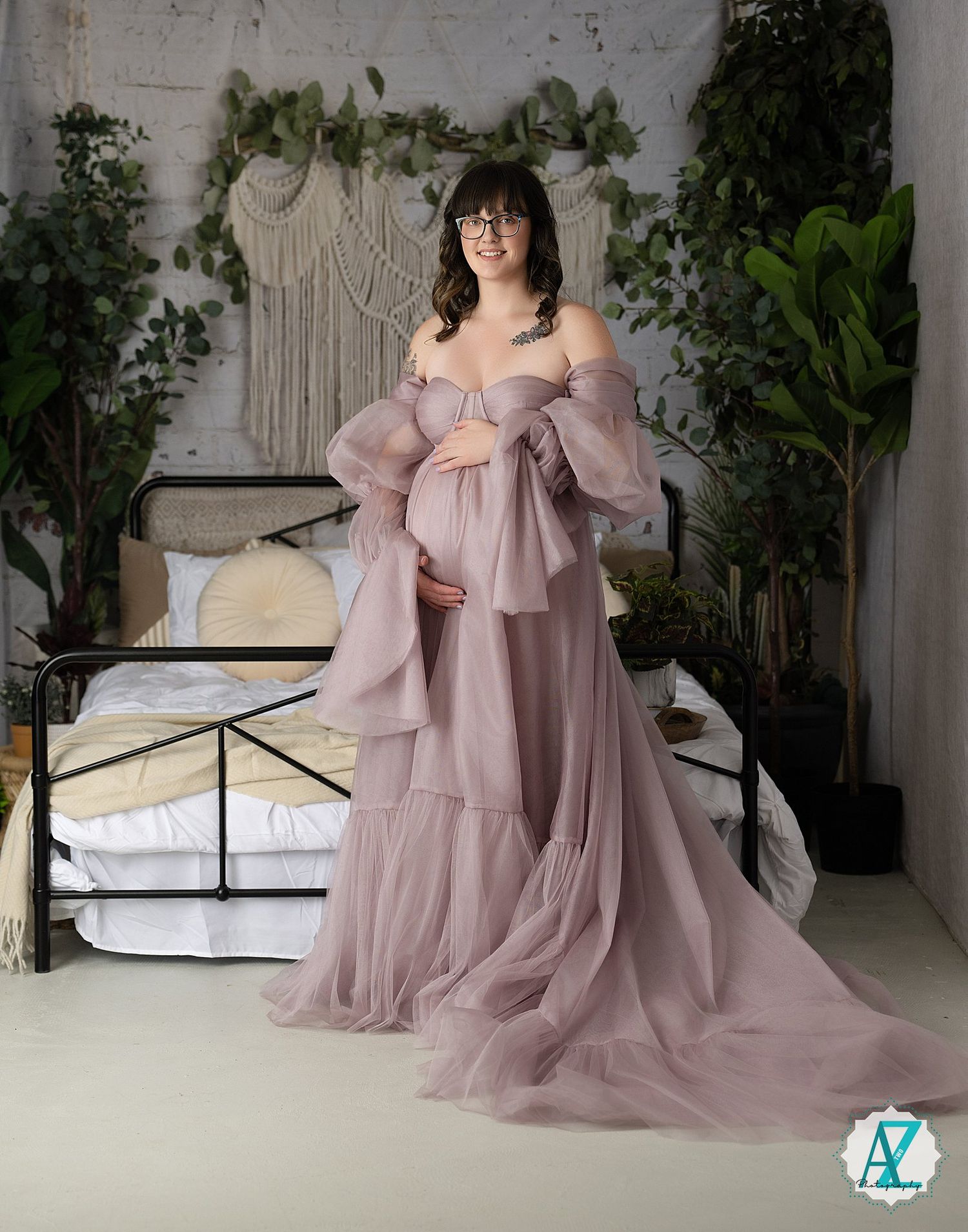 Ethereal maternity photoshoot featuring a flowing mauve tulle gown in a bohemian bedroom setting with macrame wall art.
