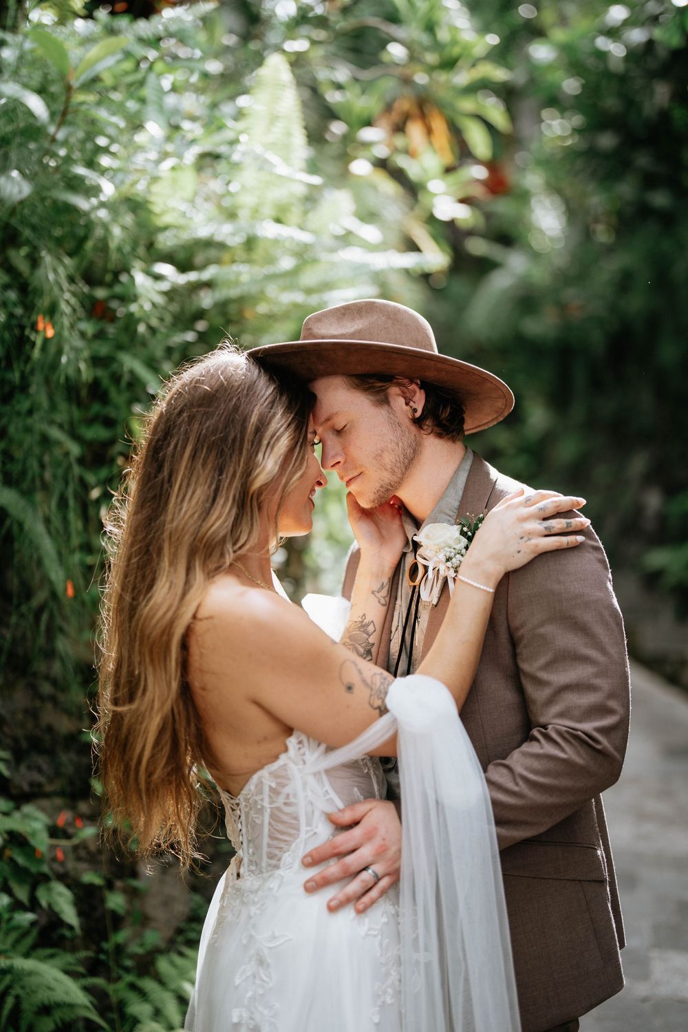 A romantic couple shares an intimate moment in a tropical garden setting.
