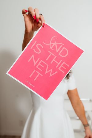 Hand holding pink promotional card against white background.