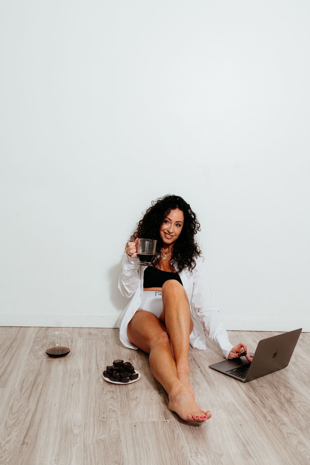 Person lounging on wooden floor with laptop and cookies while working from home.