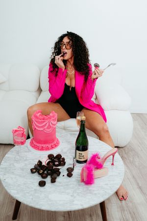 A pink cake and champagne bottle arranged on a marble coffee table with chocolate truffles.
