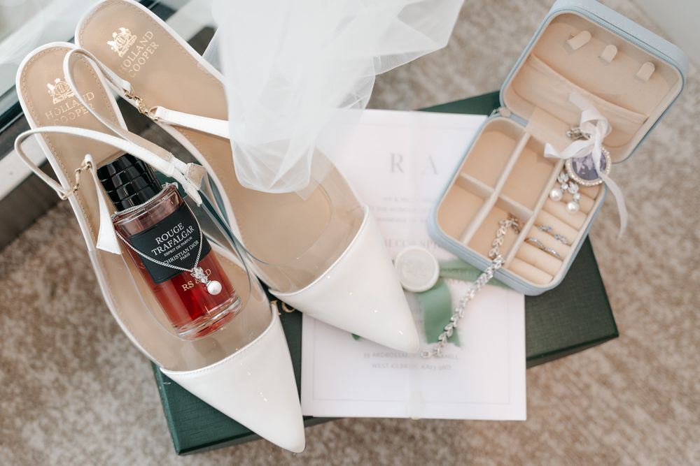 Wedding accessories including white shoes and delicate floral details on beige carpet.