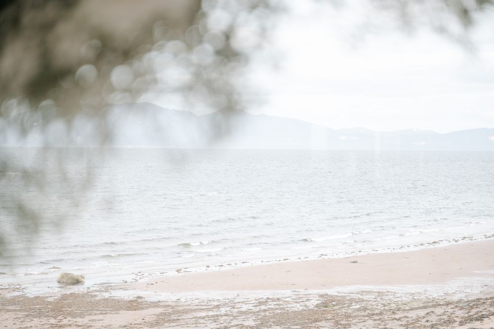 Misty beach landscape with soft waves rolling onto shore in ethereal lighting.