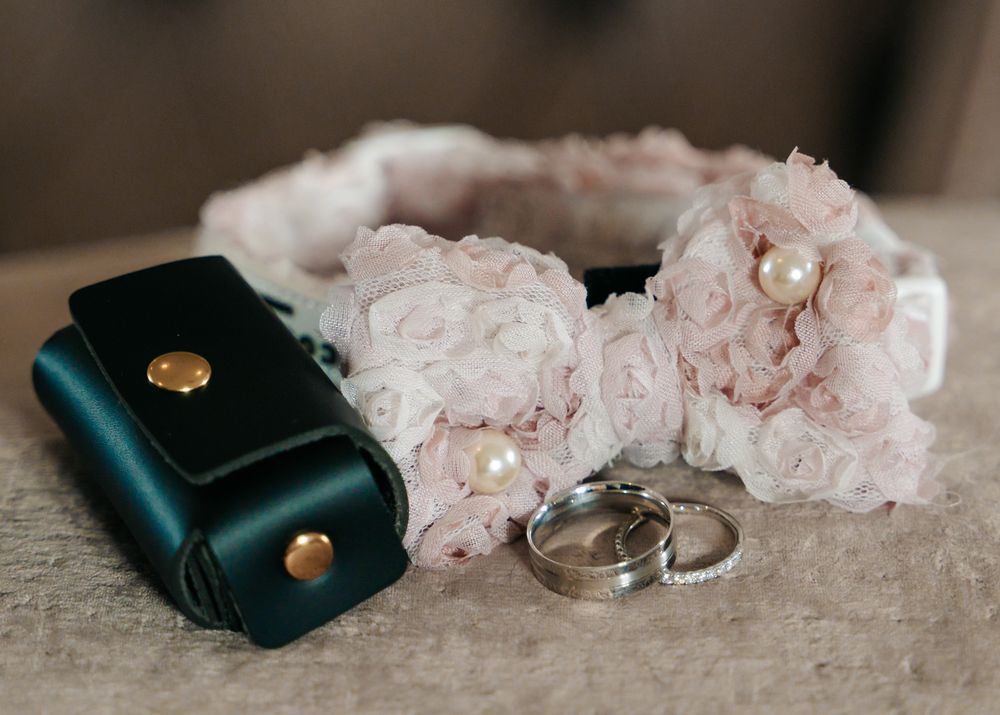 Wedding details featuring pink floral arrangements and black ring boxes on neutral surface.