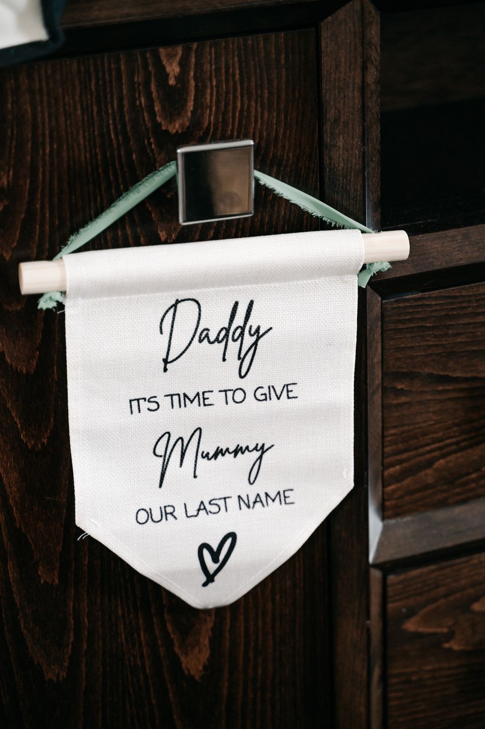 A series of hanging signs with romantic messages displayed on white paper banners against a dark wooden background.