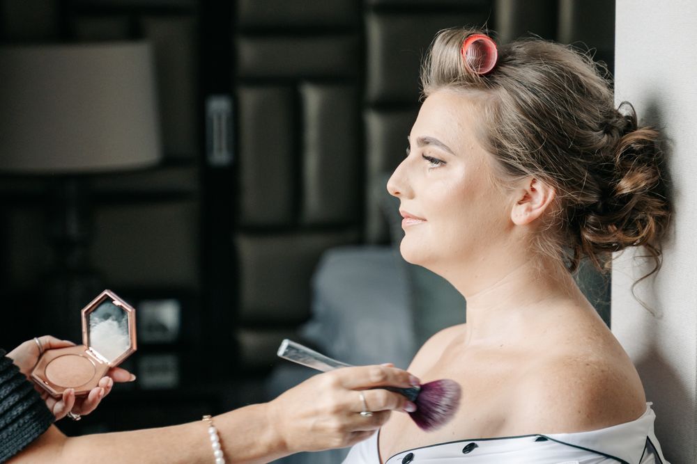Group of people getting their hair and makeup professionally done during pre-wedding preparations.