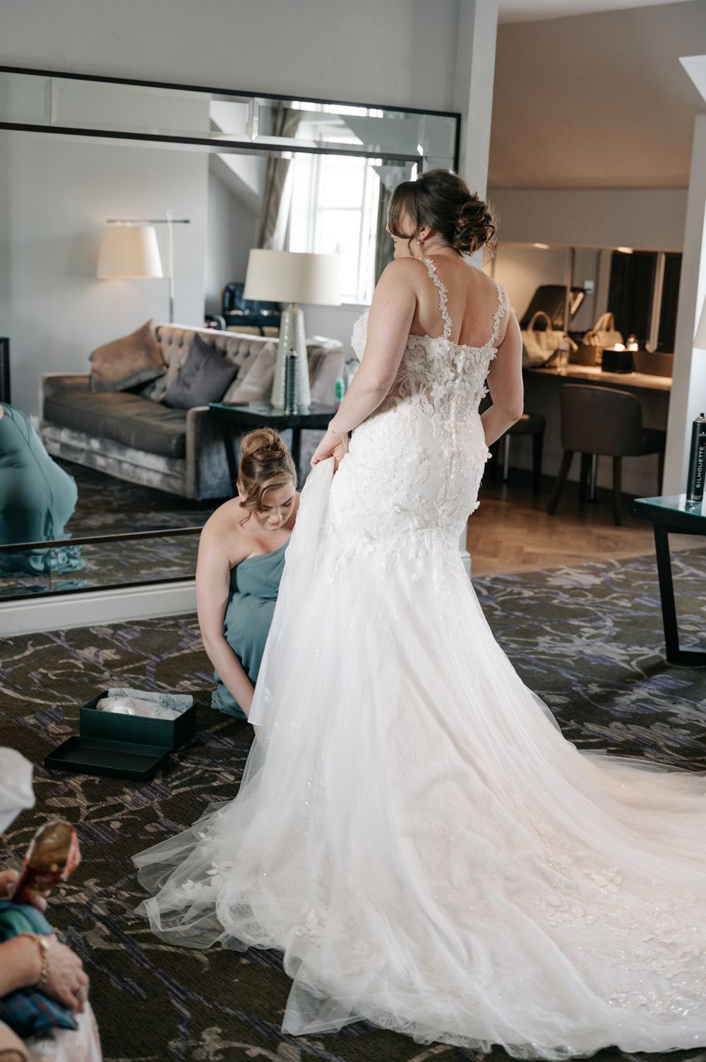 A beautiful white lace wedding dress being fitted and adjusted during pre-ceremony preparations.