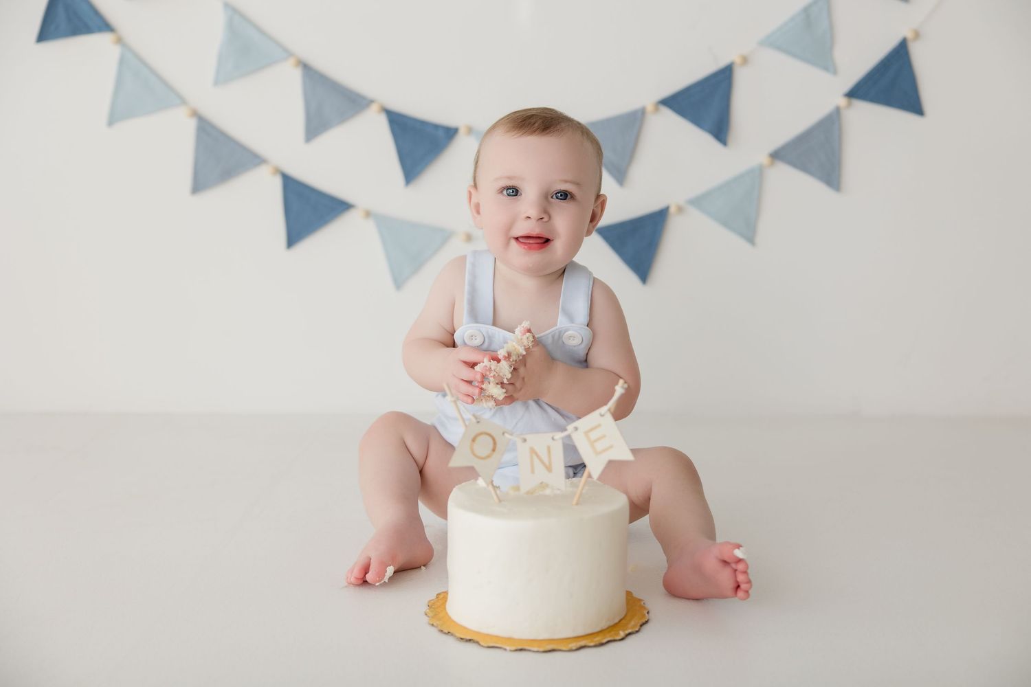 Four connected photos showing a decorated white and gold cake with blue bunting flags hanging above it.