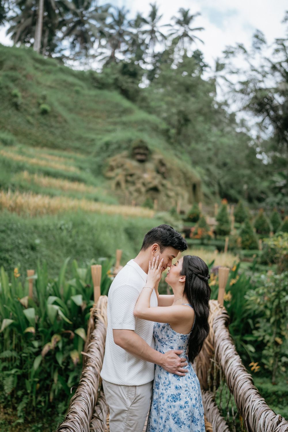 An intimate moment shared on a rope bridge in a lush tropical garden setting.