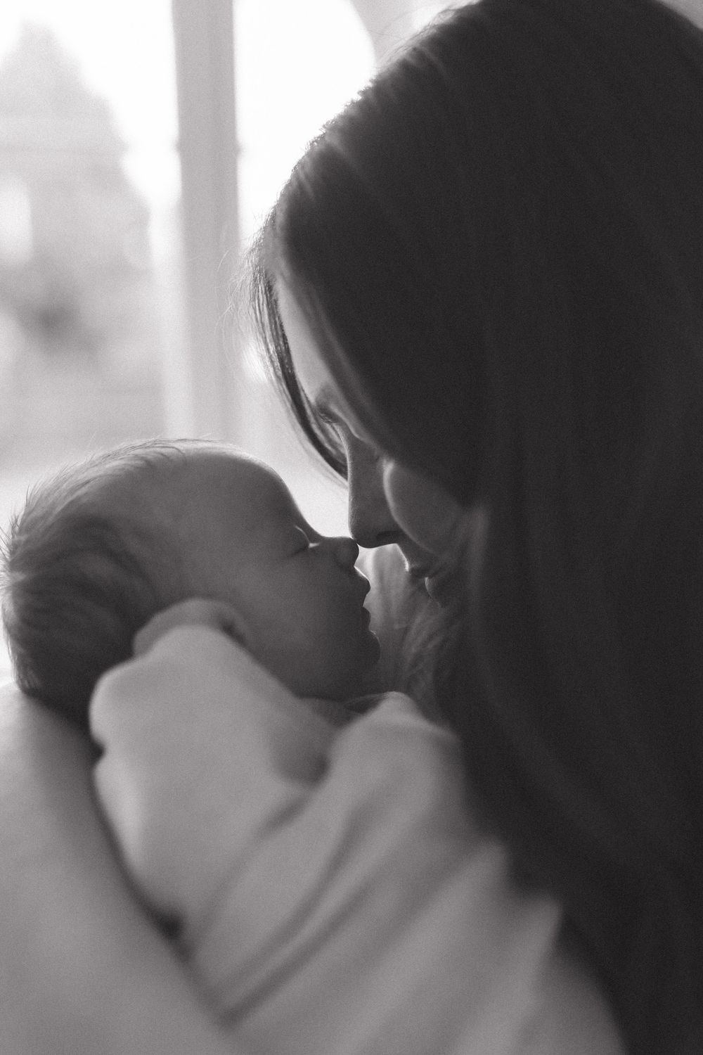 Intimate black and white portrait of tender moment between parent and sleeping infant.