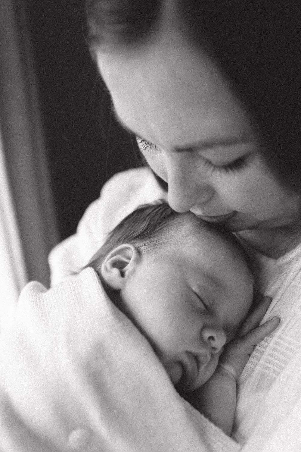 A series of black and white close-up shots showing tender moments with a baby.