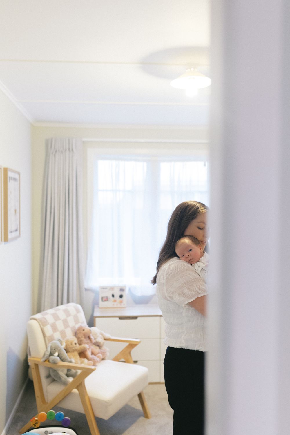Bright nursery interior with rocking chair and white curtains near large window.