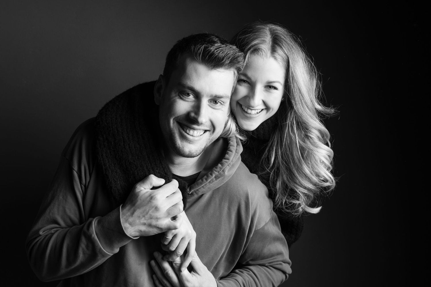 Schwarz-weiß Portrait eines Pärchens im Fotostudio Gelsenkirchen Hassel-sie umarmt ihn zärtlich, aufgenommen vom Fotograf in Gelsenkirchen