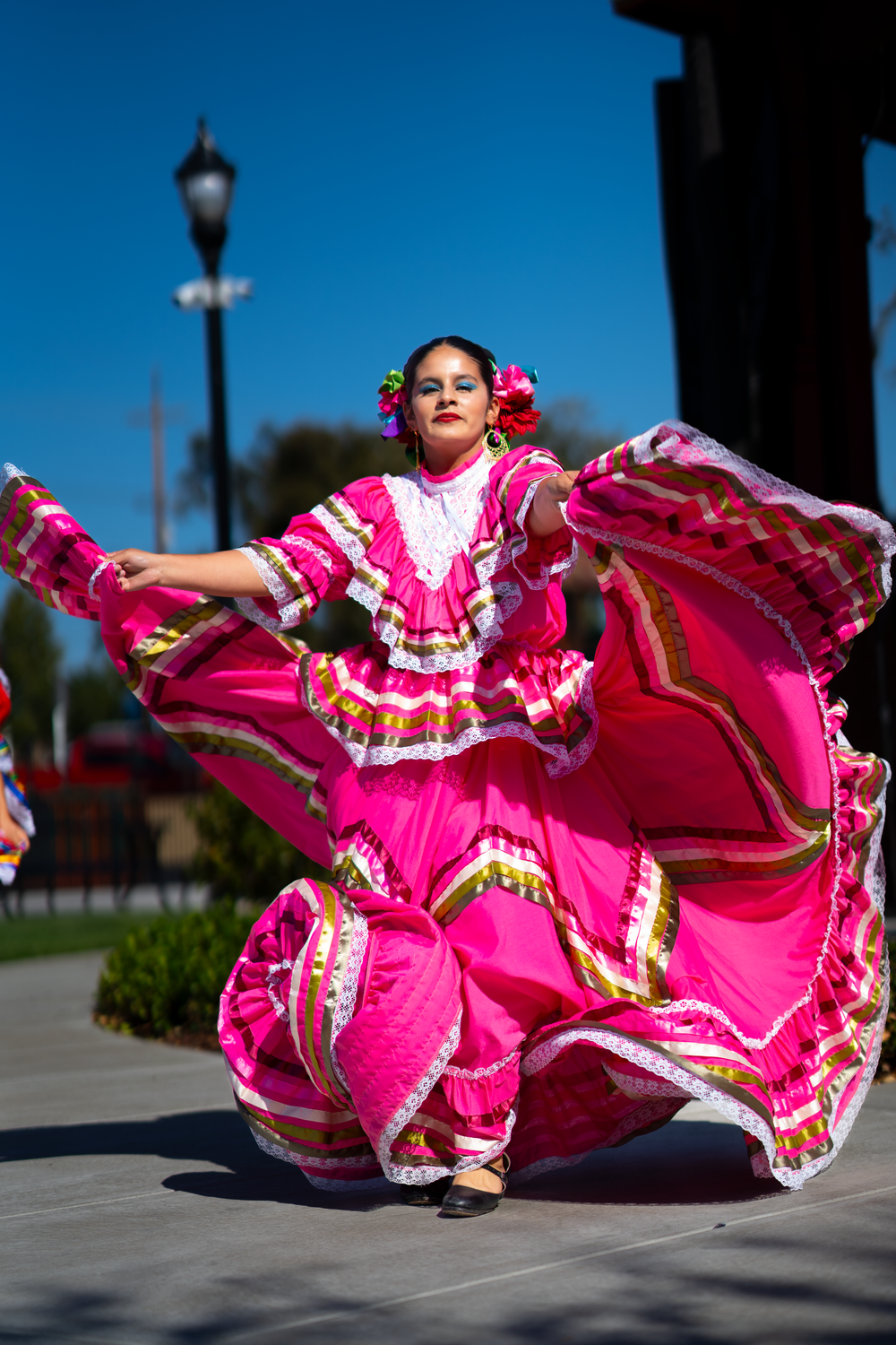 Dancers in bright pink traditional Mexican dresses perform synchronized spinning movements.